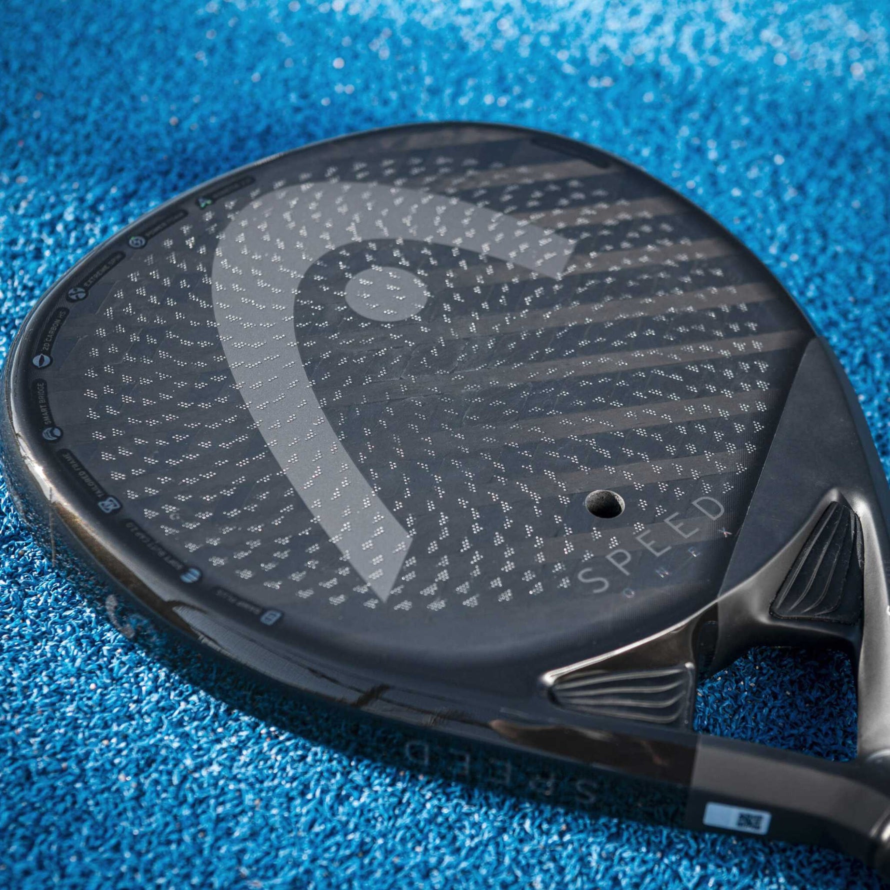 Der Head Speed One X Padelschläger auf dem blauen Court, betont die hochwertige Lackierung und Carbon-Struktur.